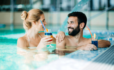 Happy attractive couple relaxing in swimming pool - Powered by Adobe