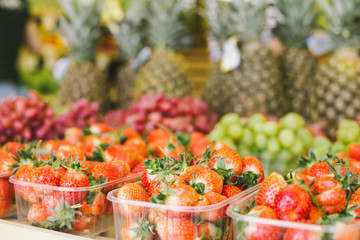 Ripe and fresh strawberries in boxes on a grocery shelf in a supermarket. Seasonal and exotic vegetables and fruits