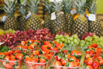 Ripe and fresh strawberries in boxes on a grocery shelf in a supermarket. Seasonal and exotic vegetables and fruits