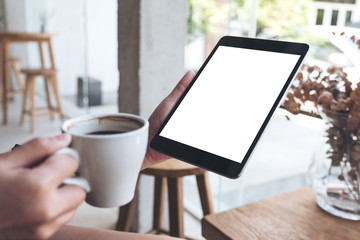 Mockup image of a woman's hand holding white mobile phone with blank desktop screen and coffee cup in cafe