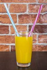 Orange juice Two straws Vitamins Health concept wooden background and brick wall
