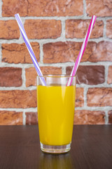 Orange juice Two straws Vitamins Health concept wooden background and brick wall