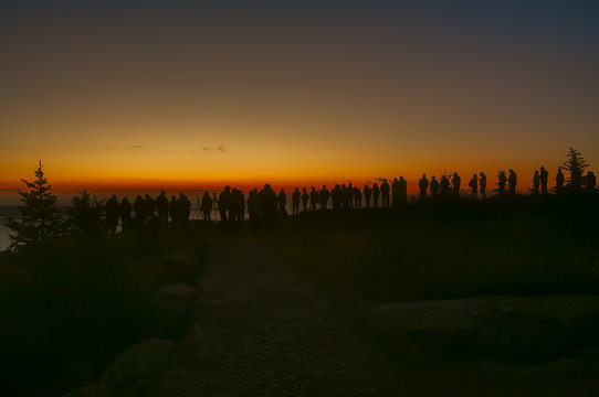 Silhouettes of so many people on the edge of the mountain in the dark awaiting the sunrise. Atlantic coast of Maine from the height of the mountains. Acadia National Park. 
