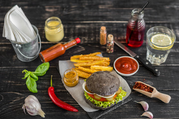Tasty hamburger with meat and vegetables against a dark background. Fast food. It can be used as a background