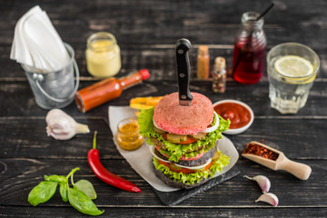 Tasty hamburger with meat and vegetables against a dark background. Fast food. It can be used as a background