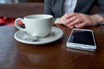 Woman hands and smart phone and cup of coffee