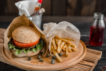 Tasty hamburger with meat and vegetables against a dark background. Fast food. It can be used as a background