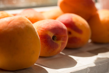 Fototapeta na wymiar Juicy fresh apricots on window counter, on natural light.