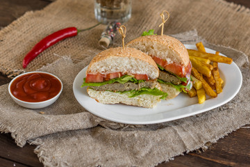 Tasty hamburger with meat and vegetables against a dark background. Fast food. It can be used as a background