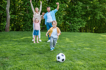 happy family playing with soccer ball in park