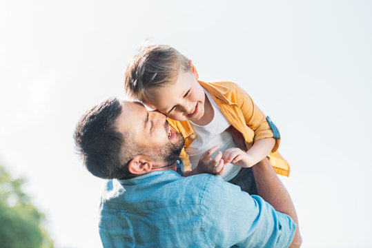happy father hugging adorable smiling little son in park