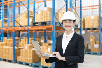 Female architect holding laptop with smiling at warehouse. People working concept.