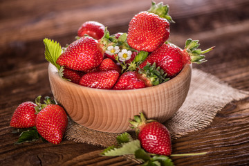 strawberries in wooden bowl on wood table