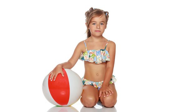 Little girl in a swimsuit with a ball