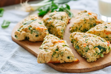 Savory scones with feta and mozarella and green herbs on a wooden board.