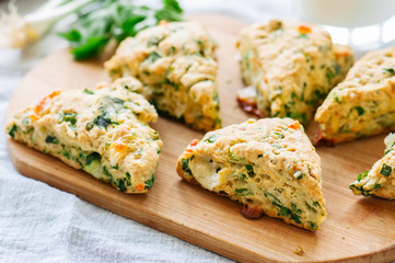 Savory scones with feta and mozarella and green herbs on a wooden board.