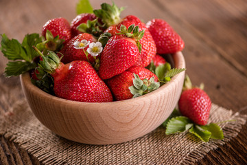 strawberries in wooden bowl on wood table