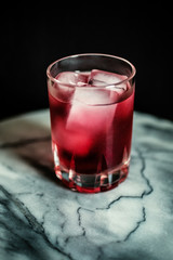 tumbler with icy red drink on marble table