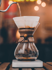 Closeup of boiling water pouring into glass flask with coffee