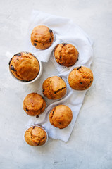 Muffins with chocolate chips and orange zest on a white stone background. Top view.