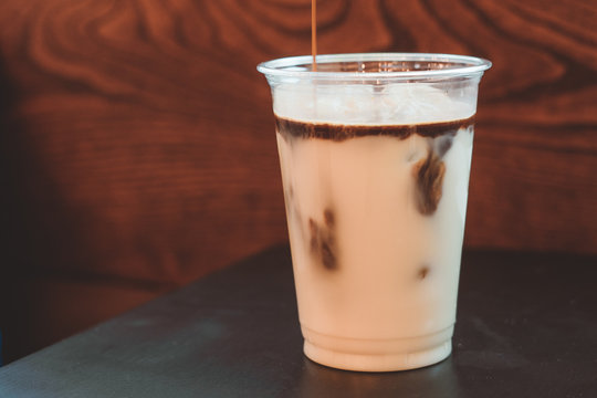 Pouring Ice Latte Coffee With Milk On Wooden Background Close Up