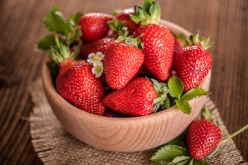 strawberries in wooden bowl on wood table