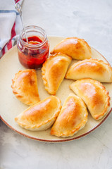 Homemade potato stuffed empanadas with ketchup on a plate. White stone background. Overhead view.