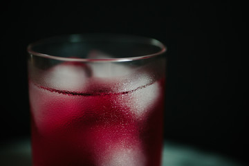 low key cold pink cocktail with ice cubes and condensed water on glass