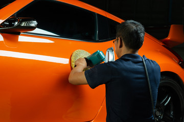 Car detailing series: Polishing orange sports car spoiler door - Powered by Adobe