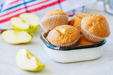 Gluten free almond flour muffins with apples in a bowl on a white stone background.