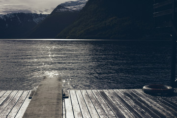 Wooden path over the water of a lake with snowy mountains