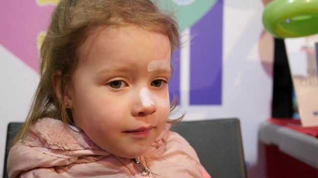 Painting body art on a face of little child girl