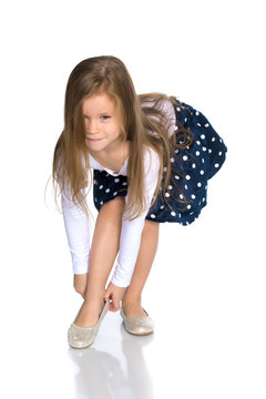 The little girl puts on her shoes.