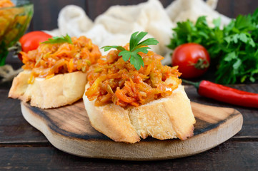 Squash caviar on a crispy baguette on a dark wooden table. Sandwiches with stewed vegetables. Vegan appetizer.