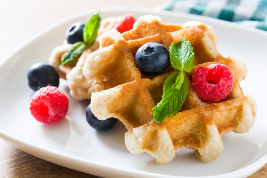 Traditional belgian waffles with blueberries and raspberries on wooden table