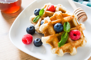 Traditional belgian waffles with blueberries and raspberries on wooden table