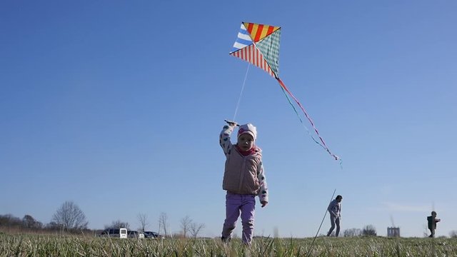 Little child girl enjoy walking with flying kite, have fun on nature picnic