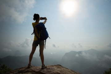 Successful woman hiker taking photo in the sunrise mountain top