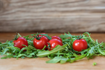 cherry tomatoes and arugula leaves on wooden background