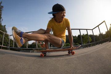 Young woman practicing yoga (Bakasana Crane Pose) on skateboard at skatepark ramp