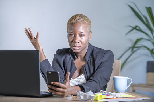 Young Desperate And Stressed African American Business Woman Working At Laptop Computer Desk At Office Suffering Stress Problem Using Mobile Phone