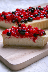 Dessert cheesecake with redberries and blueberries on wooden board and sugar powder. Close up