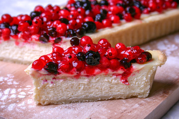 Dessert cheesecake with redberries and blueberries on wooden board and sugar powder. Close up