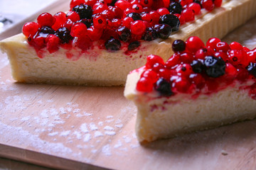 Dessert cheesecake with redberries and blueberries on wooden board and sugar powder. Close up top view