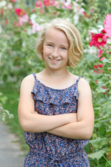 Cheerful blonde girl on a walk in the garden on a background of blooming flowers