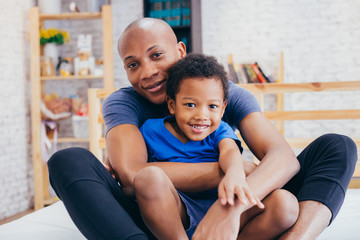 Fototapeta premium Lovely father and smiling son hugging and playing together in indoor home