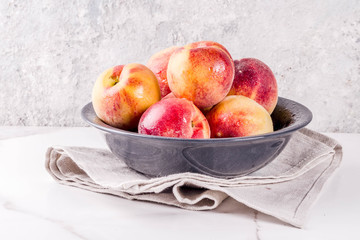 Raw fresh peaches in bowl on grey concrete background copy space