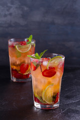 Strawberry mojito cocktail with berries, lime, mint and ice, black background. Summer berry cocktail