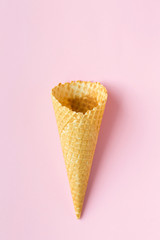 Flat-lay of waffle sweet cone over pastel light pink background, top view.