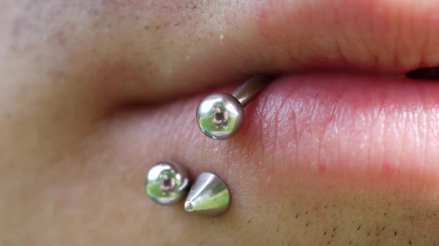Close up of a mans metal lip piercing and bar